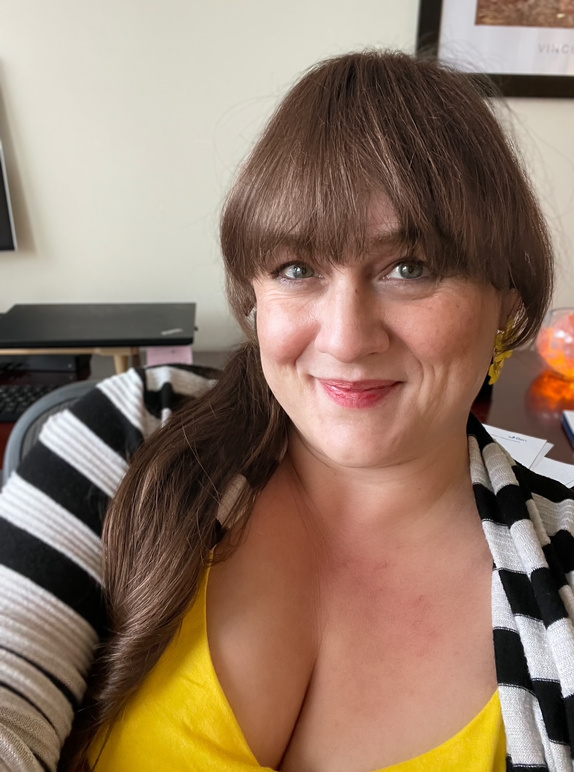 Candid photo of Rebecca Romero smiling warmly at the camera in an office setting.